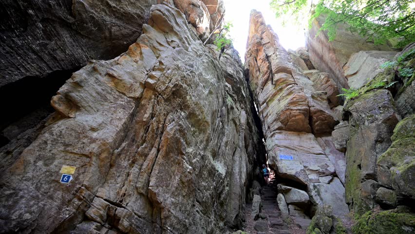 Female hiker exploring the Rock formations at Berdorf in Luxembourg during summer on Mullerthal hiking trail	