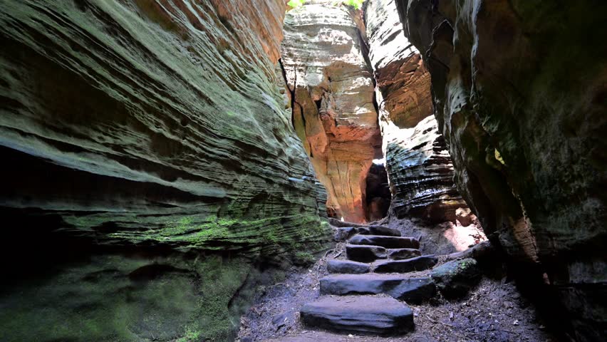 Female hiker exploring the Rock formations at Berdorf in Luxembourg during summer on Mullerthal hiking trail	