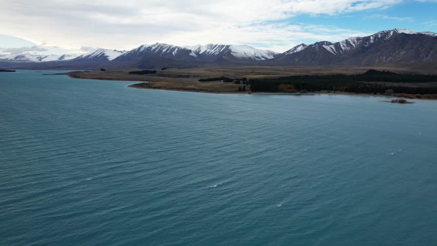 Snowy Mountain Range With Lake Tekapo In The Foreground In South Island, New Zealand. - aerial shot