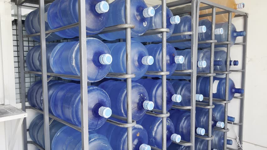 Blue plastic water bottles organized in a metal storage rack under daylight conditions