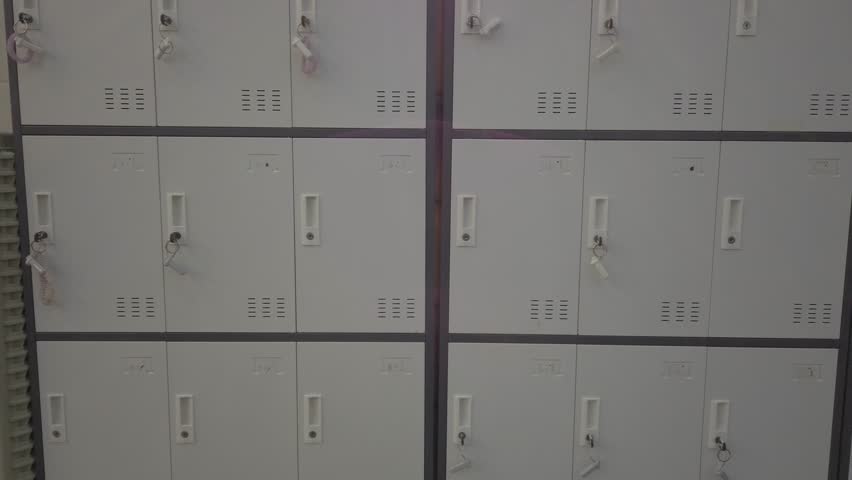 Pan right showing locked storage lockers with keys in indoor corridor, flat lighting