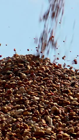 Crushed stone and gravel tumbling down a large pile as it's dropped from a conveyor belt - close-up slow-motion