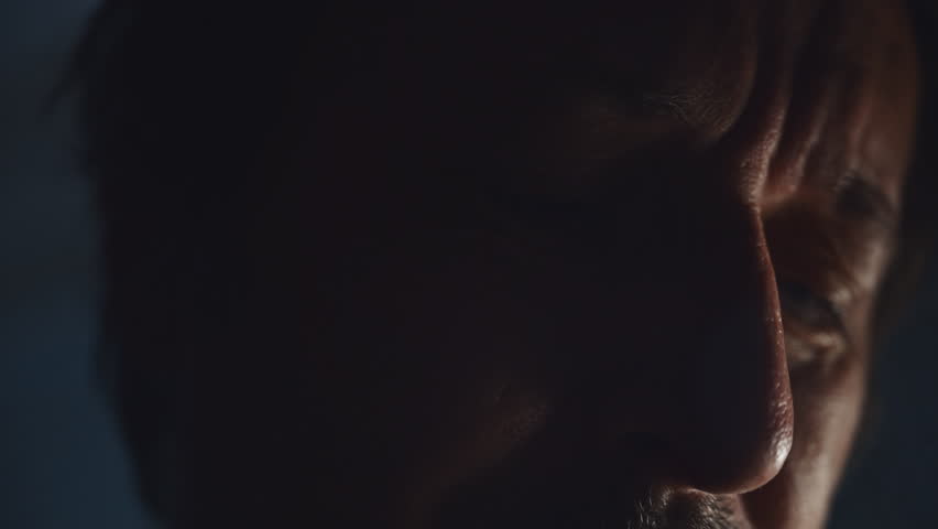 Close-up of man's teary eyes in dark, emotional expression in low-key lighting symbolizing sadness and mental struggle, 4K with selective focus