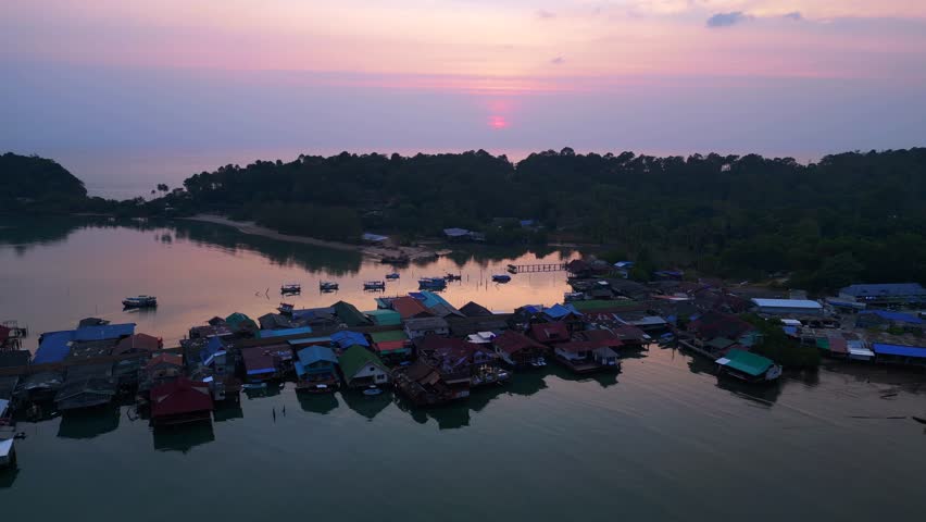 Bang Bao Pier close up, traditional fishing stilt houses reflecting on calm sea at sunset in Koh Chang, Thailand. Amazing aerial view flight panorama overview drone