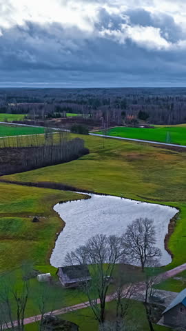 Vertical View Of A Pond Amidst Green Rural Landscape Near Isolated Cabin. Timelapse