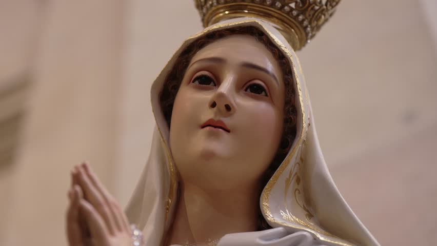 detailed close up of virgin mary statue wearing crown and white robe in prayer