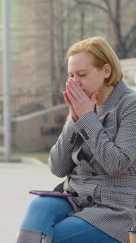 FHD vertical footage of a 40 years old woman receives the message and is insanely upset. She lowers her head and wraps her arms around it.