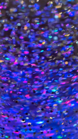 Slow motion cinematic 4K B roll footage of purple glitter abstract background with sparkling particles creating eye-catching visual effect in vertical format. This aesthetic b roll captures the high-resolution shimmer with clean composition and dramatic lighting perfect for social media and digital promotions. The faceless b roll features minimalist style framing with copy space ideal for storytelling visuals, commercial background, wallpapers, and marketing use. High resolution cinematic footage showcases the mesmerizing glitter movement, vibrant purple tones, and luxurious sparkle atmosphere with glamorous visual flow, perfect for modern lifestyle branding, beauty marketing, fashion advertising campaigns, celebration content, event projects, social media stories, corporate presentations, and creative projects requiring eye-catching abstract and elegant shimmer visuals.
