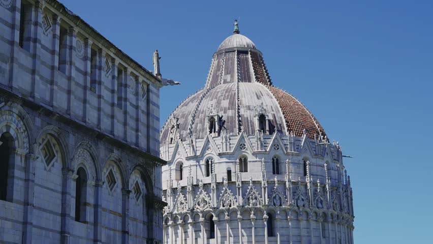 The detailed dome and facade of the Battistero di San Giovanni in Pisa, Italy, showcase an exquisite blend of Romanesque and Gothic architectural styles located in Piazza dei Miracoli