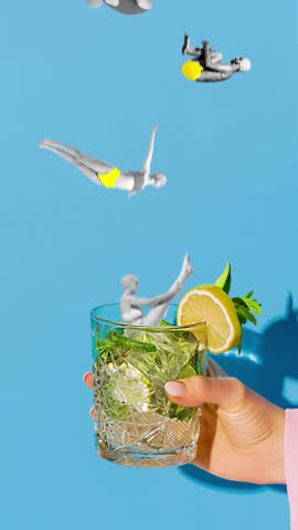 Playful stop motion. Swimmer jumping into glass of lemonade held by hand against blue background. Concept of summer, holidays, celebration, Friday mood, festivals.