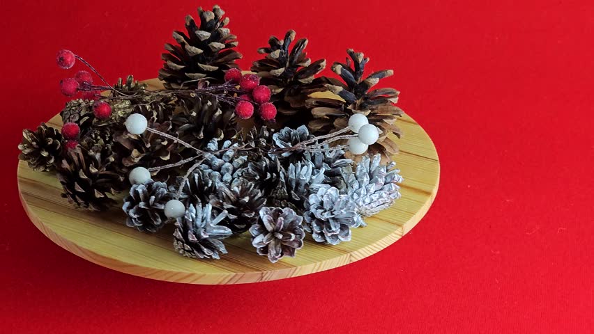 New Year's set for creativity. Cones, painted cones and rowan berries in glaze on a rotating wooden board. Red background.
 - Powered by Shutterstock - Get 15% off with code: PIKWIZARD15