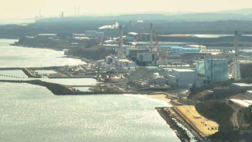 Aerial view of the Fukushima Daiichi Nuclear Power Plant, showing a mix of industrial buildings, water storage, and coastal structures, Okuma, Fukushima, Japan.
