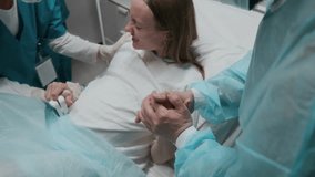 Medium shot of pregnant young Caucasian woman lying on bed in delivery room at maternity hospital, experiencing labor pain, screaming, breathing, while husband in holding hand and midwife counting - Powered by Shutterstock - Get 15% off with code: PIKWIZARD15