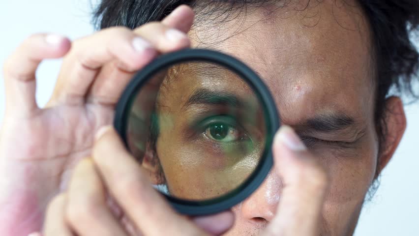 a man checks how dense his camera's ND filter is before attaching it to the camera