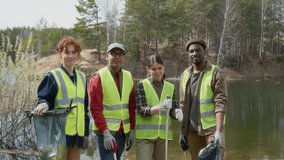 Group of young biracial volunteers dressed in uniform just gathered in local forest, standing together holding plastic bags and trash pickers. They looking at camera and smiling - Powered by Shutterstock - Get 15% off with code: PIKWIZARD15