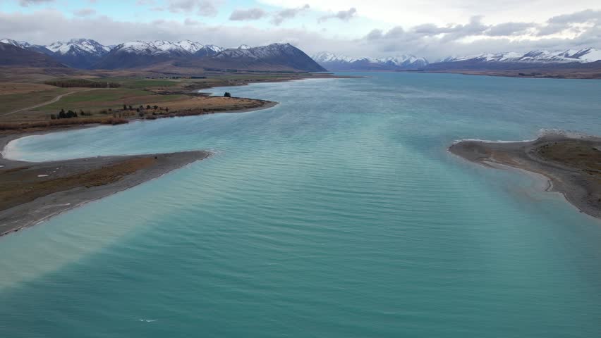 Stunning Turquoise Blue Waters Of Lake Tekapo With Mountain Views In South Island, New Zealand. - aerial shot