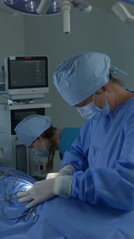 Vertical video of Veterinarians prepare a dog for surgery in the operating room of an animal clinic, time lapse shot. Vet healthcare and medicine concepts.