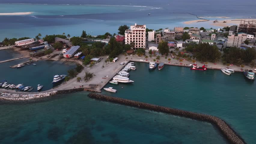 Aerial view of the tranquil Gulhi harbor, with boats resting on the turquoise waters contrasting with the town
