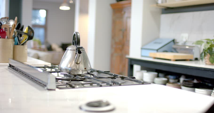 Camera is capturing steel kettle resting on gas stovetop since start to showcase kitchen. Metalware, cookware, culinary, minimalist, rustic, home, domestic