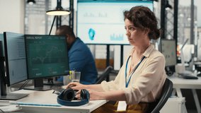 Female executive consultant listening to songs on headphones at the workstation, managing administrative tasks to ensure company productivity and efficiency. Woman reviews data. Camera B. - Powered by Shutterstock - Get 15% off with code: PIKWIZARD15