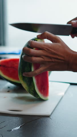 Chef slices watermelon on a white cutting board