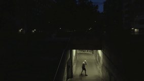 Dolly shot of a lone figure in a hoodie practicing boxing in a dim, graffiti-covered underpass at night, evoking resilience and determination. - Powered by Shutterstock - Get 15% off with code: PIKWIZARD15