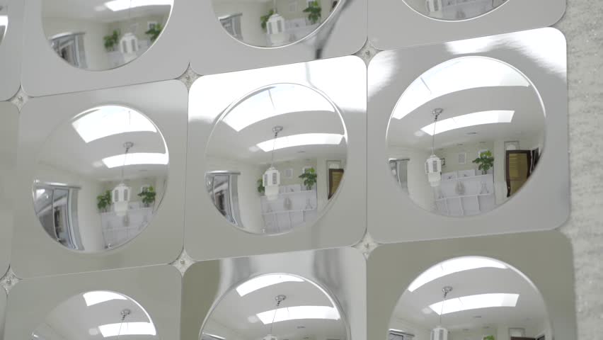 This video shows a close-up panning of a chrome geometric mirror wall from the 1970s, featuring bold op art design and reflective surfaces in a vintage retro-modern aesthetic.