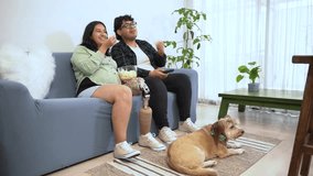 Expecting parents enjoy a relaxing evening, watching television and eating popcorn, accompanied by their furry friend - Powered by Shutterstock - Get 15% off with code: PIKWIZARD15