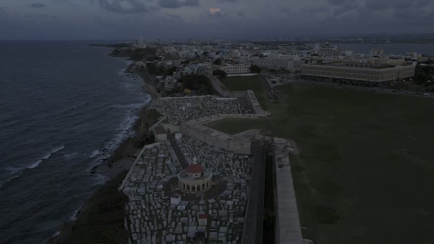 Drone flies east over cemetery after sunset in historic city center in San Juan, Puerto Rico