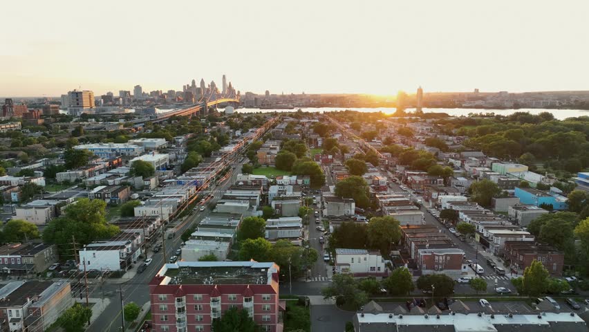 Wonderful neighborhood of Camden in New Jersey with green trees along roadside summer. Skyline of Philadelphia and famous Benjamin Franklin bridge in distance. Quiet and peaceful atmosphere in USA.