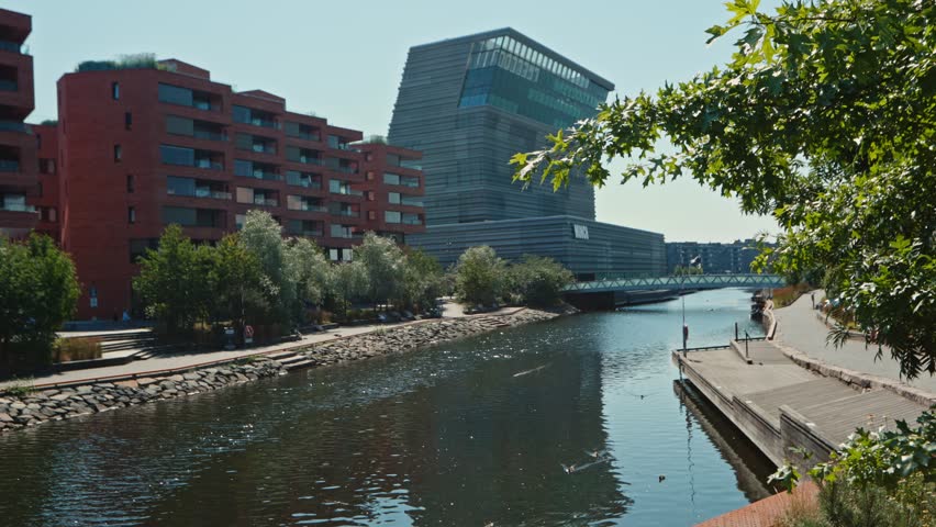 Clear day exterior Munch Museum in Bjørvika, Oslo, with canal and modern residential buildings.