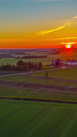 Vertical View Of Vibrant Sunset Over Vast Landscape Of Farmlands. Aerial Pullback Shot