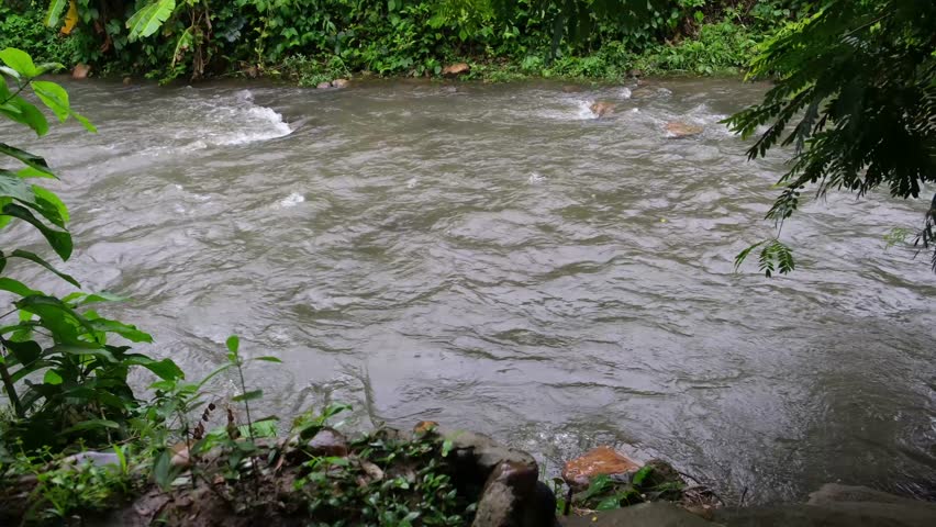 Water stream in a canal flowing down while it's raining