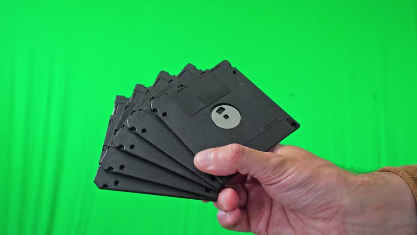 A nostalgic and technical mood is captured as a hand holds a fanned stack of classic 3.5-inch floppy disks, ready for integration into various digital or historical themes - Powered by Shutterstock - Get 15% off with code: PIKWIZARD15