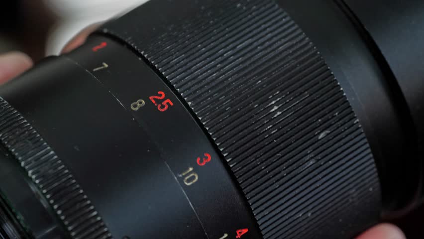 A detailed and technical mood is captured by a close-up of the aperture and focus rings on a vintage camera lens, highlighting the numerical markings and intricate design