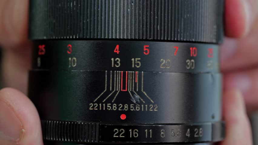 A detailed and technical mood is captured by a close-up of the aperture and focus rings on a vintage camera lens, highlighting the numerical markings and intricate design