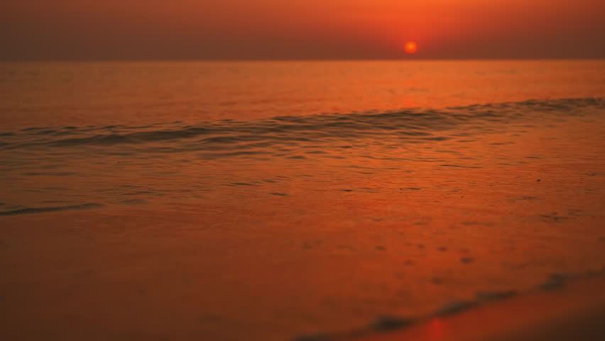 Close-up of calm waves running onto the shore, video of sunset over the sea, late evening walk along the seashore after the daytime heat, fantastic view of the evening sea