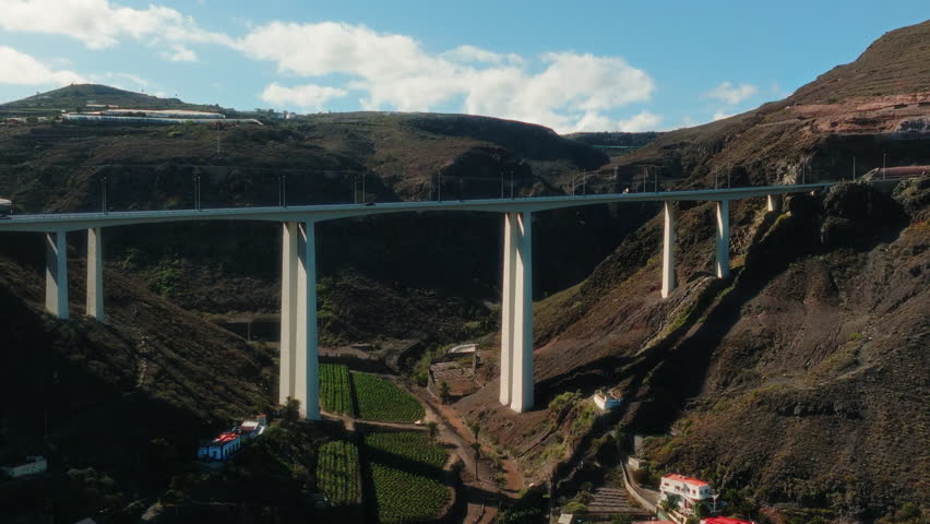 Aerial: white bridge in a valley with cars and traffic during the day in Gran Canaria, Spain, establishing drone shot