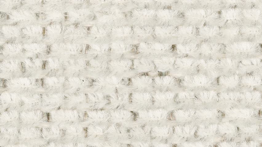 Macro shot slowly pans, revealing plush white carpet and subtle grey motif