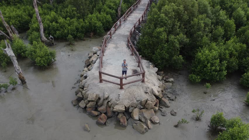 aerial panoramic view of male model flying drone at the swampy mangrove beach landscape