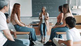 Mature high school teacher and a group of students are engaged in an inspirational lecture, conversation, and debate - Powered by Shutterstock - Get 15% off with code: PIKWIZARD15