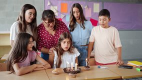 Celebrating girl birthday party at Primary School together with friends and teacher, blowing cake candles - Powered by Shutterstock - Get 15% off with code: PIKWIZARD15