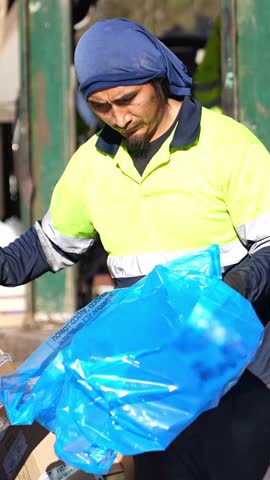 Waste management worker managing various recyclable materials like cardboard, plastic, and wood, captured in a slow motion sequence
