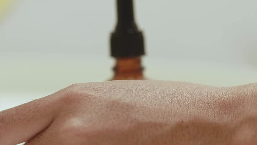 Close up to testing serum from a brown glass bottle with dropper on skin of a hand showing skincare and cosmetic