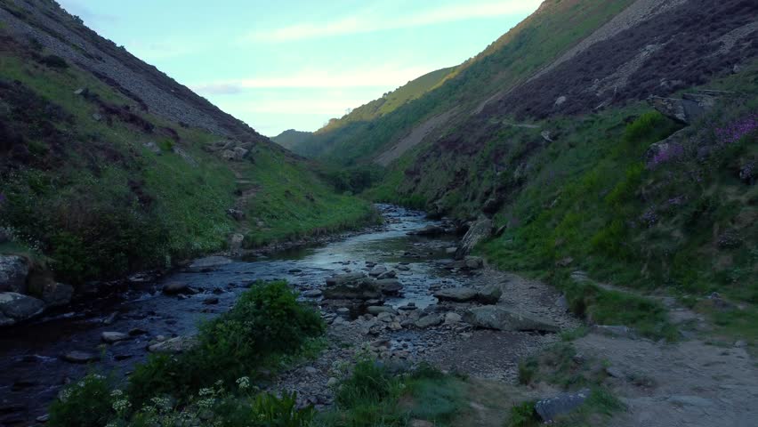 Fast Moving Aerial Heading Up River with Hiking Paths on Each Side at Sunrise with Sunlight on Top of Valley. Natural Bird