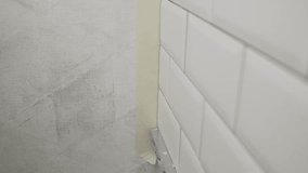 Professional builder carefully protecting pristine white ceramic tiles with precision masking tape during detailed home renovation process - Powered by Shutterstock - Get 15% off with code: PIKWIZARD15