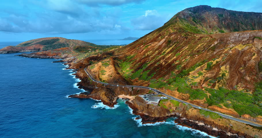 View on the road crossing the rocky shore of the Pacific Ocean. Volcanic mountains of Oahu, Hawaii, USA. Aerial perspective.