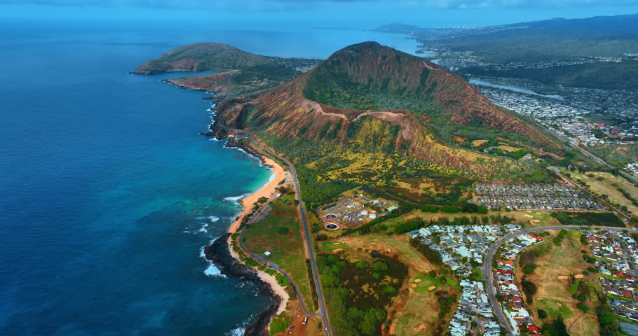 Flight over the picturesque shore of Oahu, Hawaii near the Pacific Ocean. View on the Diamond Head Crater surrounded by residential area.