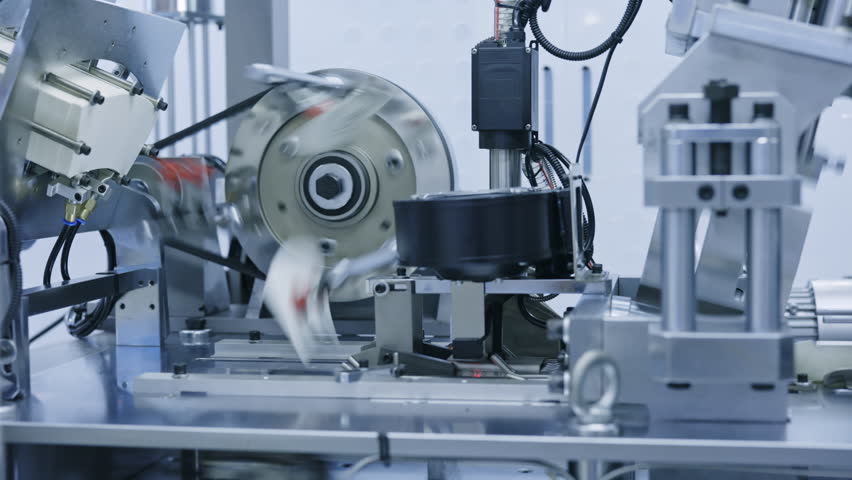Close-up of high-speed industrial machine producing paper cups. Modern food packaging equipment in motion, used for eco-friendly disposable tableware manufacturing.