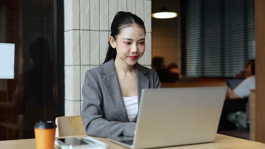 Professional young Asian businesswoman working intently at cafe table, focused on laptop screen while typing and engaging with digital project, embodying modern entrepreneurial lifestyle - Powered by Shutterstock - Get 15% off with code: PIKWIZARD15